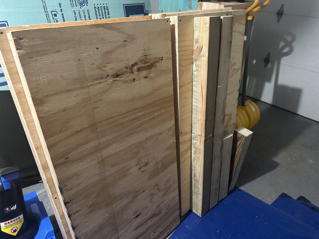 Four sections of cut 4"x4" pressure treated lumber, 4 2'x4' shelves stacked up waiting for assembling.

Also pictured: a snow shovel and part of a snowblower because it may be the end of April, but it's Michigan, so who knows.